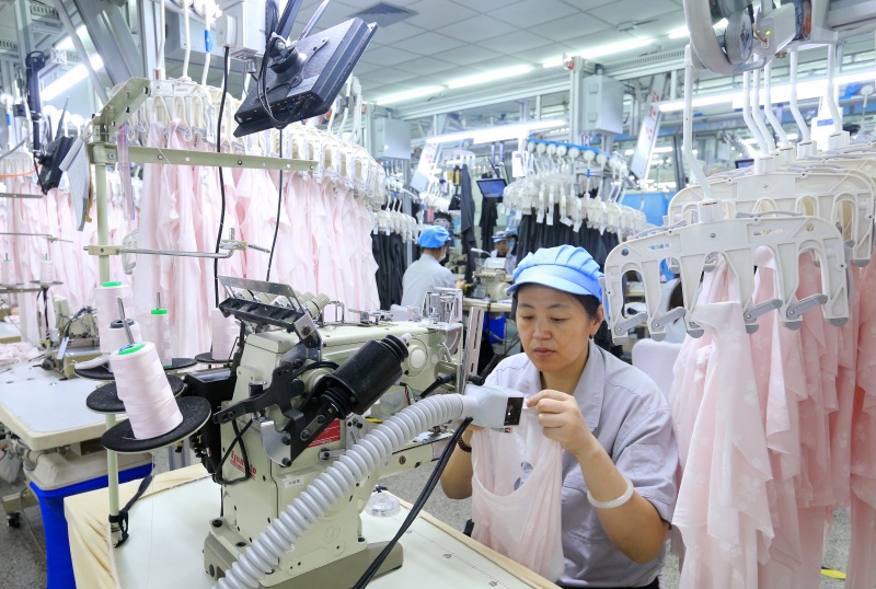 9月16日，山东省青岛华诺针织有限公司的员工在智能吊挂生产线上生产出口到海外市场的服装产品。