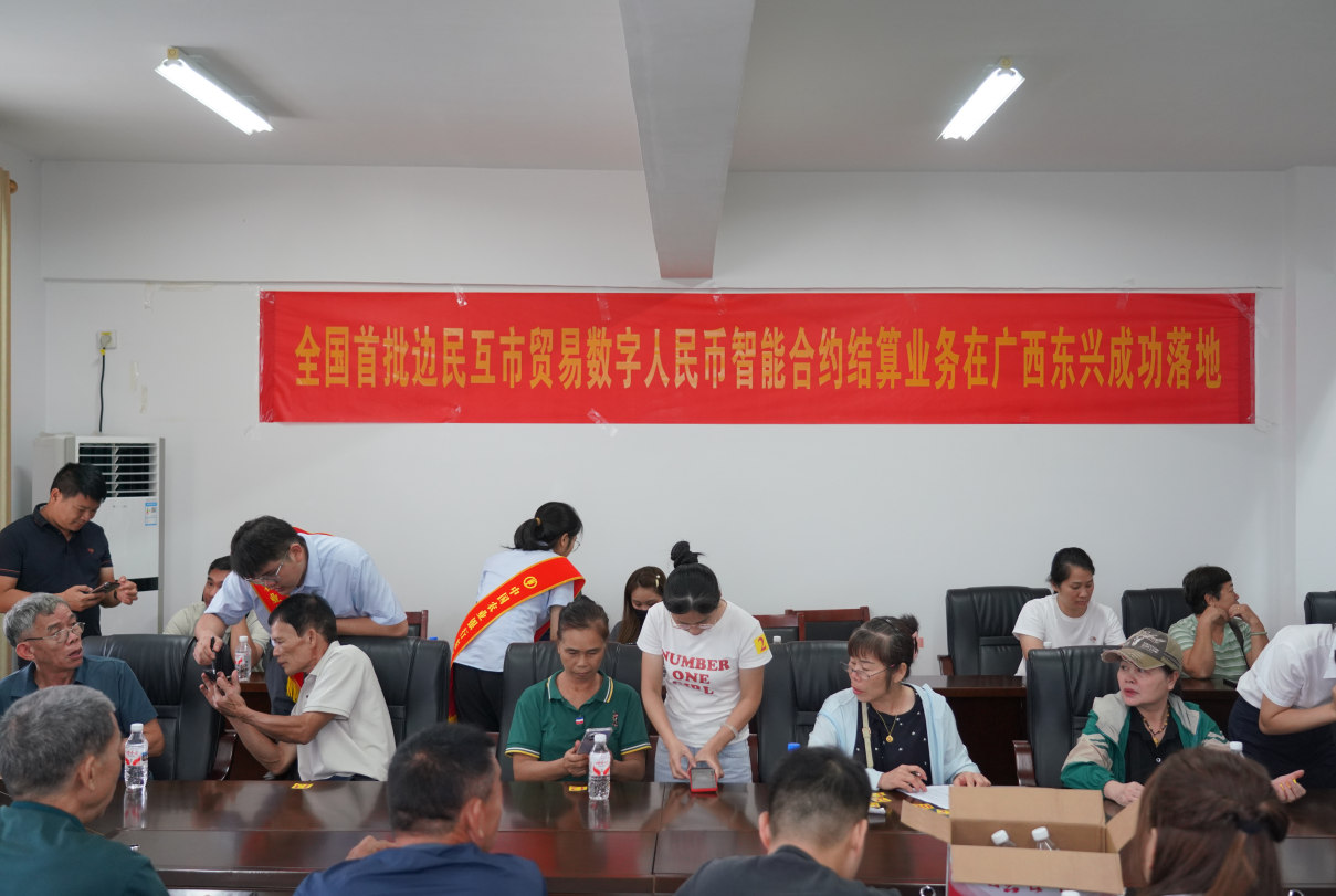 农行员工现场指导边民开通数字人民币个人钱包。