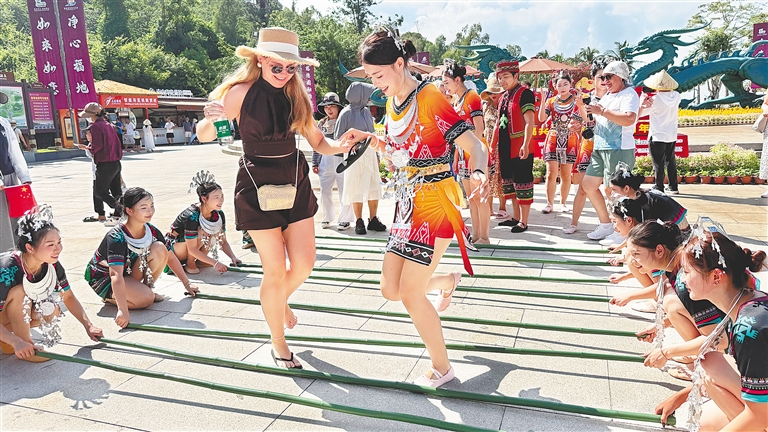 10月1日,外国游客在三亚南山文化旅游区体验非遗竹竿舞。新华社发