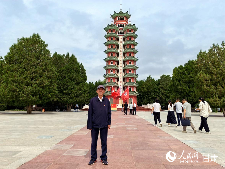 王文汉在会师塔前拍照留念。人民网记者 周婉婷摄