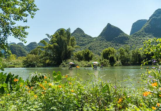 游客在遇龙河上乘坐竹筏,感受山水之美。