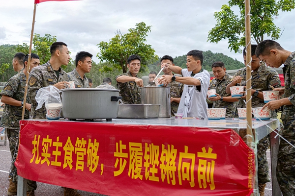 图2为武警官兵在美食节主食区有序领取餐食。梁景润摄