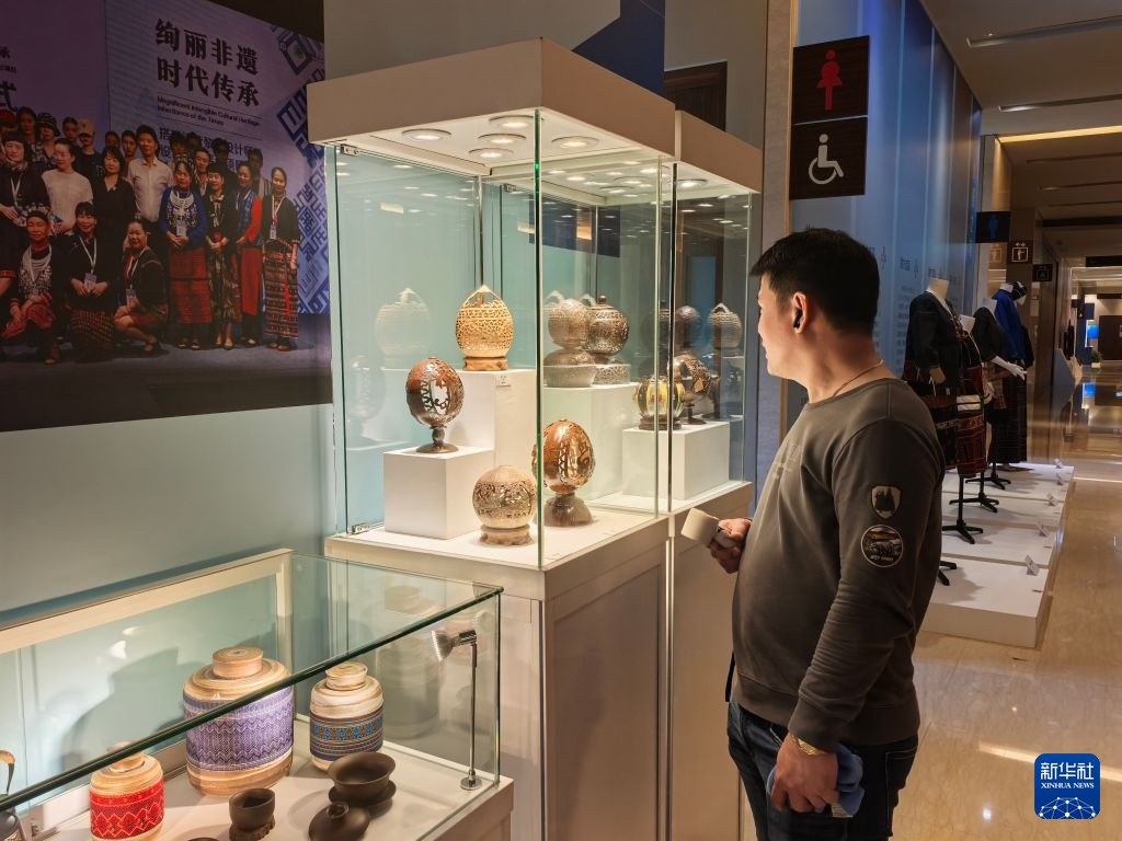 10月3日,菲律宾游客在海南非物质文化遗产主题展上参观椰雕展品。新华社记者 马欣然 摄